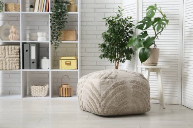 Masada tropikal canavar yaprakları olan modern bir oturma odası ve şık bir puf.