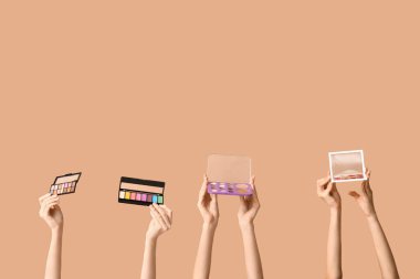 Kahverengi arka planda farklı göz falı paletleri olan kadın elleri