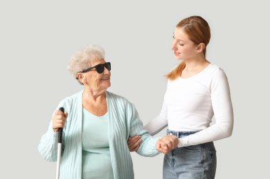 Açık arkaplanda kör büyükannesi olan genç bir kadın.