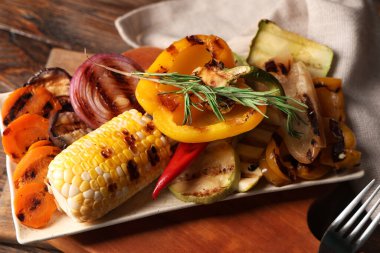 Lezzetli ızgara sebze tabağı ve ahşap arka planda biberiye.