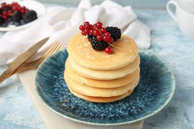 Taze böğürtlenli krep tabağı ve açık mavi arka planda kırmızı frenk üzümü.