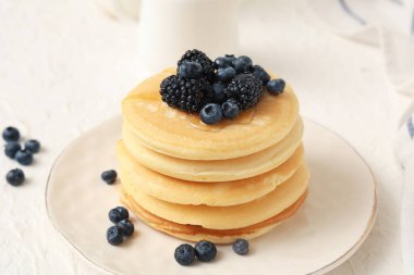 Beyaz arka planda taze yaban mersinli ve böğürtlenli bir tabak tatlı krep.