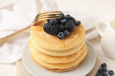 Beyaz arka planda taze yaban mersinli ve böğürtlenli bir tabak tatlı krep.