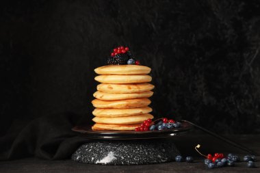 Siyah arka planda farklı taze böğürtlenli tatlı krep tabağı