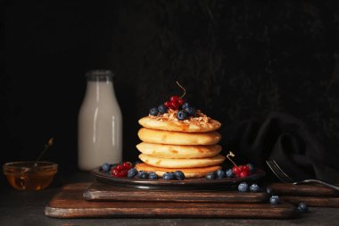 Taze böğürtlenli, fındıklı ve siyah arka planda bal dolu bir tabak tatlı krep.
