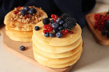 Beyaz arka planda taze böğürtlen ve fındıklı ahşap pankekler.