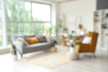 Yeşil çiçekleri, kanepesi ve koltuğu olan bulanık oturma odası.