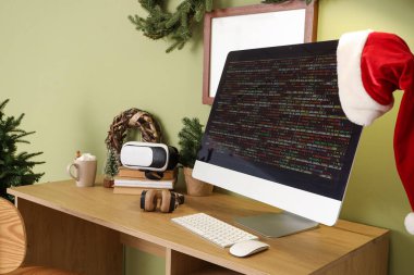 Ofisteki programcının masasında Noel Baba şapkası ve Noel dekoru olan bilgisayar monitörü.