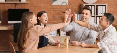 İş adamlarından oluşan bir ekip ofiste el ele tutuşuyor.