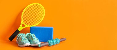 Turuncu arka planda farklı spor aletleri ve ayakkabılar.