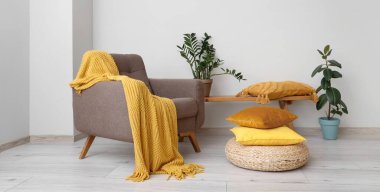 Rahat bir koltuk ve oturma odasında sıraları ve çiçekleri olan yumuşak yastıklar.