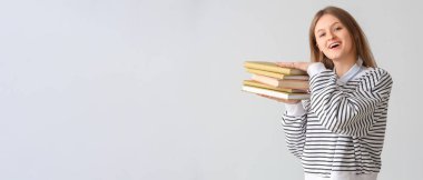 Küçük arkaplan üzerine kitap yığını tutan mutlu kız öğrenci ve metin için yer