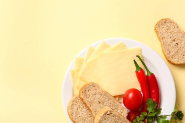 Sarı arka planda ekmek ve sebzeli lezzetli işlenmiş peynir tabağı.