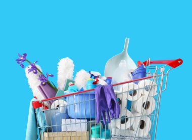 Shopping cart full of cleaning supplies and purple flowers on blue background clipart