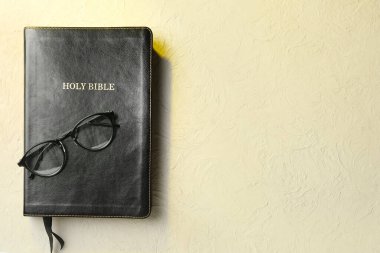 Gri arka planda gözlüklü kutsal İncil.