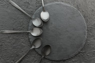 Siyah zemin üzerinde paslanmaz çelik kaşıklar olan tahta