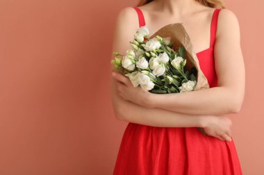 Pembe arka planda bir buket güzel Eustoma çiçeğiyle genç bir kadın.