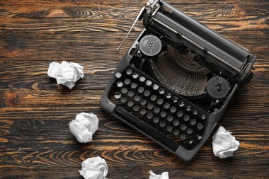 Kahverengi ahşap arka planda buruşuk kağıtlı klasik daktilo