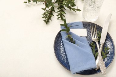 Beyaz arka planda katlanmış peçete, boş kart ve çatal bıçak takımı.