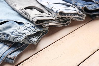 Ahşap arka planda farklı tarz kot pantolon, yakın plan.