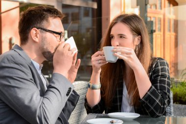 Güzel, mutlu bir çift restoranda oturuyor ve güneşli bahar gününde kahve içiyor.
