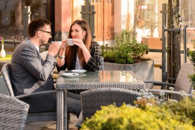 Güzel, mutlu bir çift restoranda oturuyor ve güneşli bahar gününde kahve içiyor.