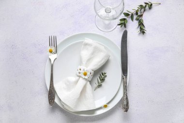 Katlanmış peçeteli tabaklar, gümüş çatal bıçak takımı ve grunge beyaz arka planda cam.