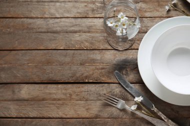 Kahverengi ahşap zemin üzerinde çatal bıçak takımı ve cam tabaklar.