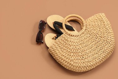 Çantalı ve kahverengi arka planda parmak arası terlikli şık güneş gözlükleri