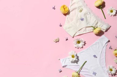 Şık kadın külotları ve pembe arka planda güzel çiçekleri olan kompozisyon