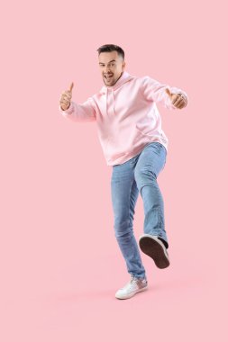 Mutlu genç adam pembe arka planda onay veriyor.