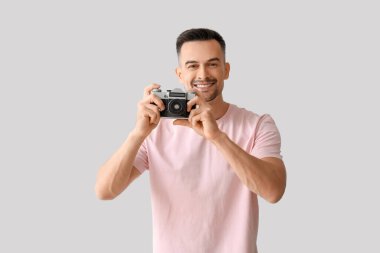 Arka planda fotoğraf makinesi olan mutlu genç bir adam.