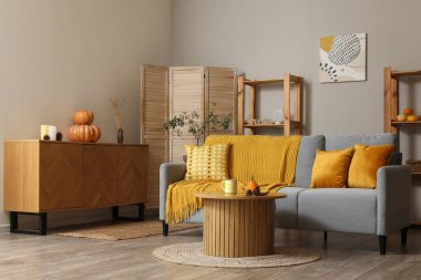 Kahve masasında gri kanepe ve balkabağı olan modern oturma odasının içinde.