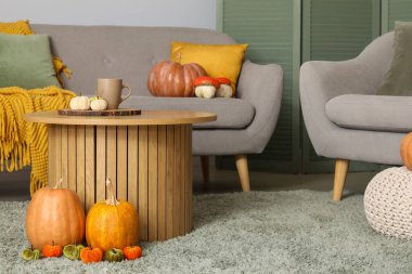 Modern oturma odasının içinde bir fincan çay ve balkabağı olan kahve masası.