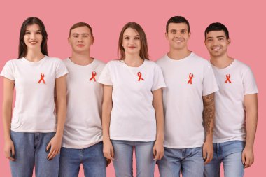 Pembe arka planda kırmızı kurdeleli bir grup genç. Dünya AIDS Günü konsepti