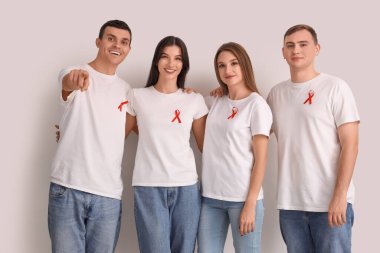 Beyaz arka planda kırmızı kurdeleli bir grup genç. Dünya AIDS Günü konsepti