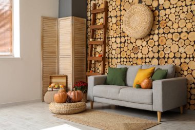 Gri kanepe, hasır puf ve balkabağı olan rahat bir oturma odası.