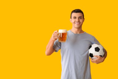 Sarı arka planda bir kupa bira ve futbol topuyla yakışıklı genç adam.