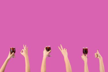 Pembe arka planda sıcak şarap kadehleriyle kadın elleri.