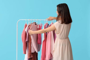 Mavi arka planda elbise askısı olan kadın stilisti