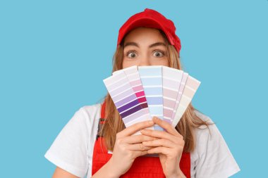 Mavi arka planda renk paletleri olan kadın ressam