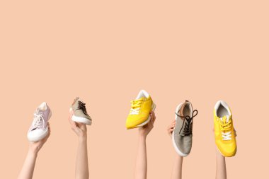 Bej arka planda farklı şık spor ayakkabıları olan kadın elleri. Ayakkabı tamiri kavramı