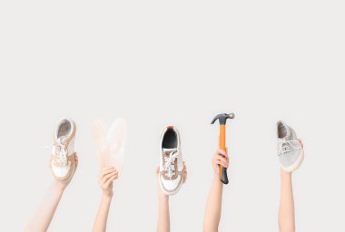 Spor ayakkabılı kadın eller, çekiç ve beyaz arka planda tabanlar. Ayakkabı tamiri kavramı