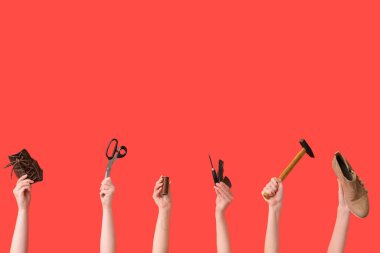 Kırmızı arka planda ayakkabı, çekiç ve el işi aletleri olan kadın eller. Ayakkabı tamir konsepti