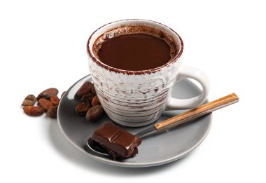 Beyaz arka planda bir fincan lezzetli sıcak çikolata, kaşık ve kakao çekirdeği.
