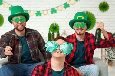 Evde bira içen, parti bardaklı komik genç adamlar. Aziz Patrick Günü kutlaması