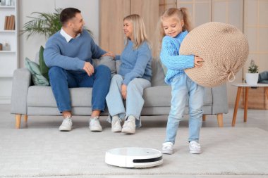 Evde puf ve robot elektrikli süpürgesi olan küçük bir kız.
