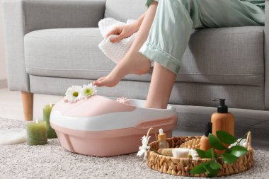 Kaplıca malzemeleri taşıyan bir kadın evde ayak banyosu yapıyor.