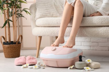 Masaj banyosu, spa malzemeleri ve evde tropik çiçekleri olan bir kadın.