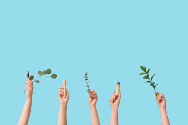 Temelli kadın elleri, kapatıcı, ruj ve mavi arkaplanda dallar